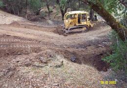 A bulldozer is used to dip the crossing fill in preparation for installation of the rock armor