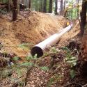 The new culvert is placed at the designed channel gradient with the culvert outlet set on the natural channel bed.